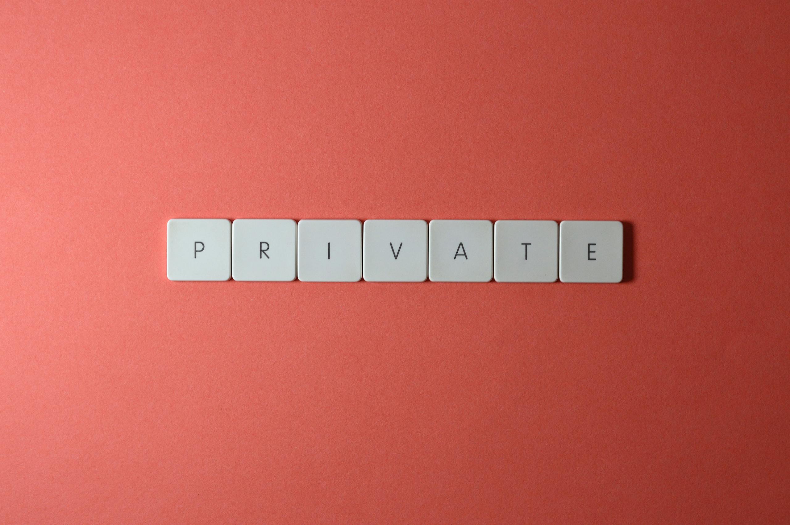 White letter tiles spelling 'PRIVATE' on a red background, offering conceptual minimalist design.